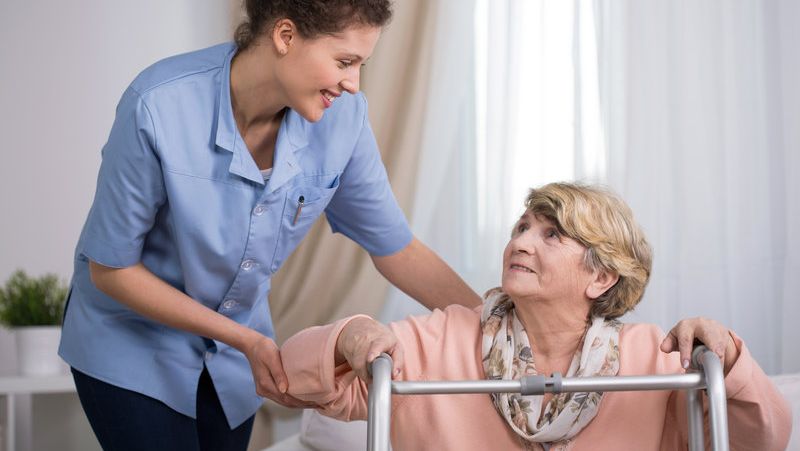 A carer helping an elderly woman