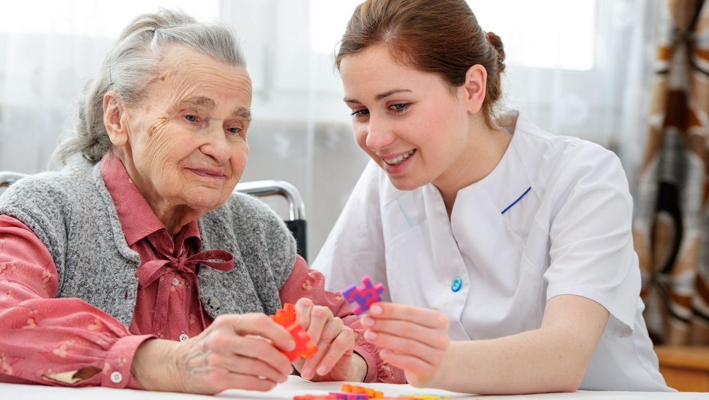 A Carer Playing a Jigsaw Puzzle with an Elderly Woman. 